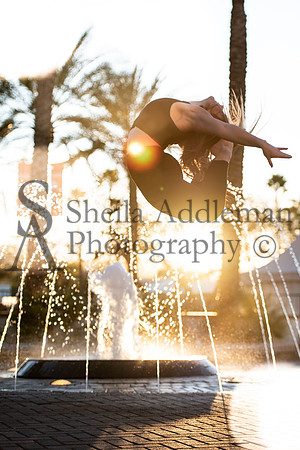 Dancer doing a C jump in front of a Water fountain